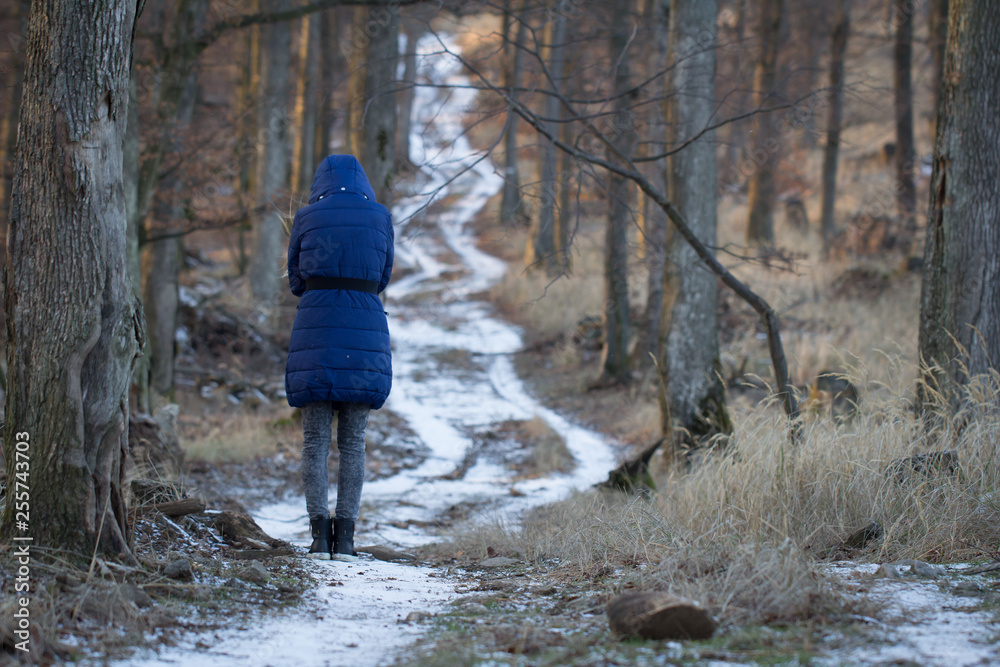 woman standing alone at winter forest path