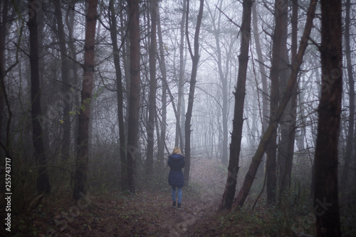 woman walking alone in dark scary forest