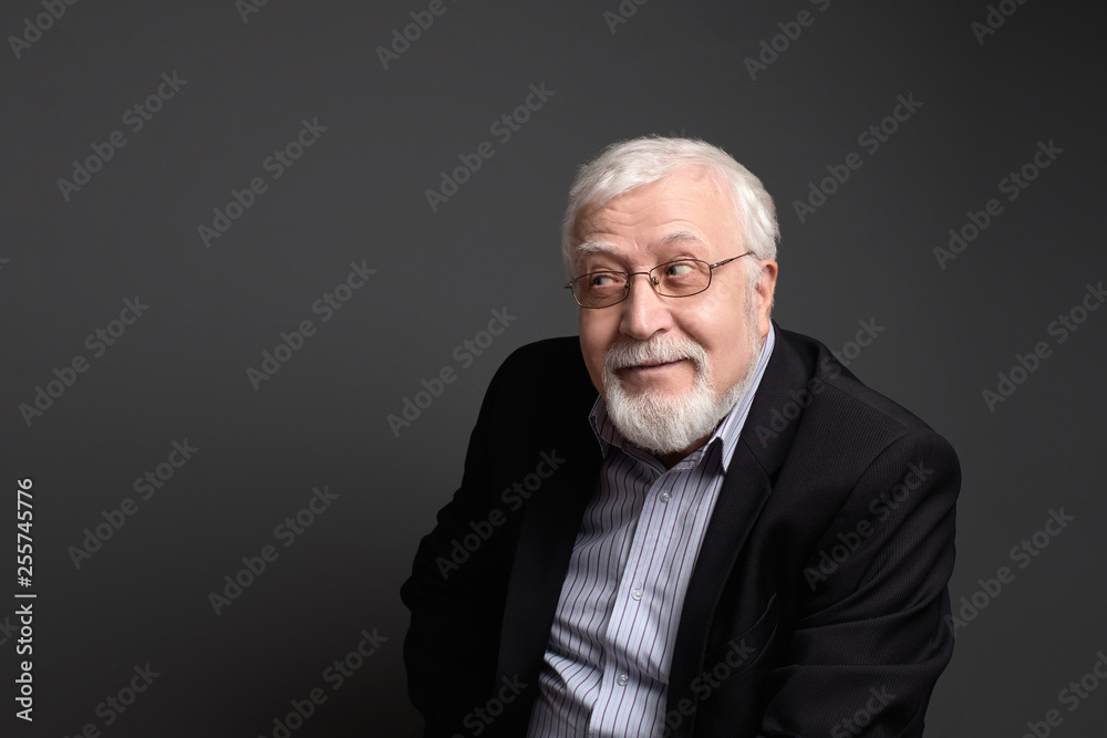 An interesting white-haired male businessman looks sly. On a gray background