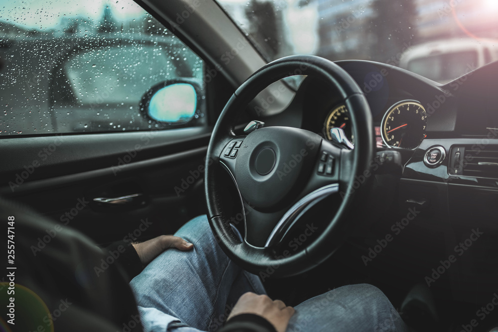 driver’s hands hold the steering wheel of a modern car while waiting for a passenger.