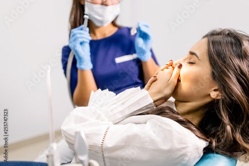 Girl in pain holding her mouth sitting in the dental office