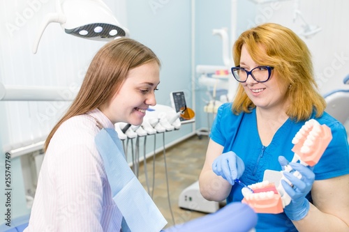 Woman dentist advises the girl showing the layout of the jaw