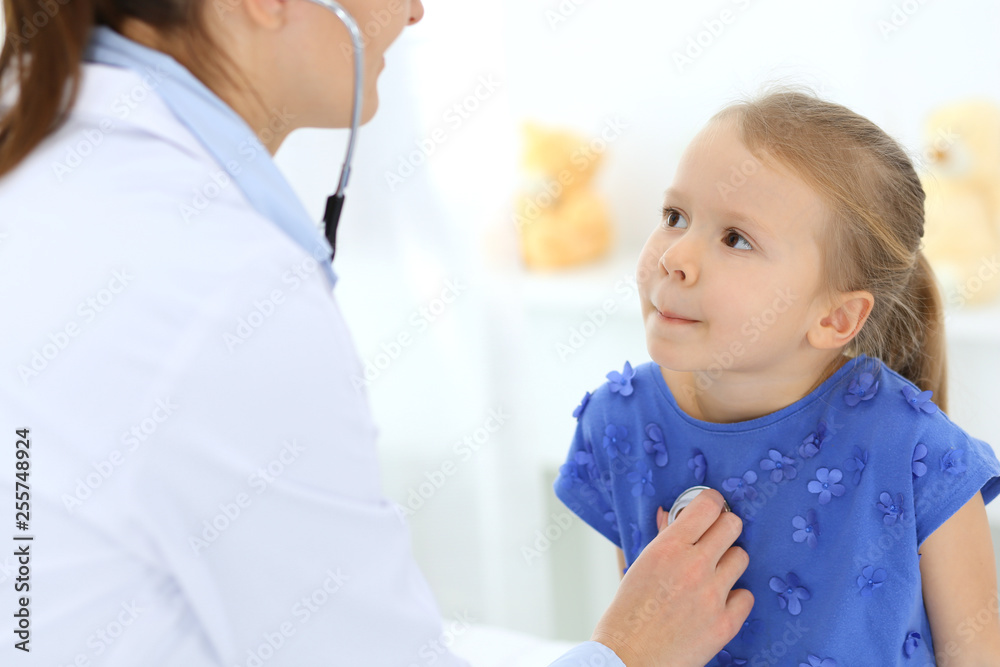 Doctor examining a little girl by stethoscope. Happy smiling child patient at usual medical inspection. Medicine and healthcare concepts Doctor examining a little girl by stethoscope. Happy smiling child patient at usual medical inspection. Medicine and healthcare concepts