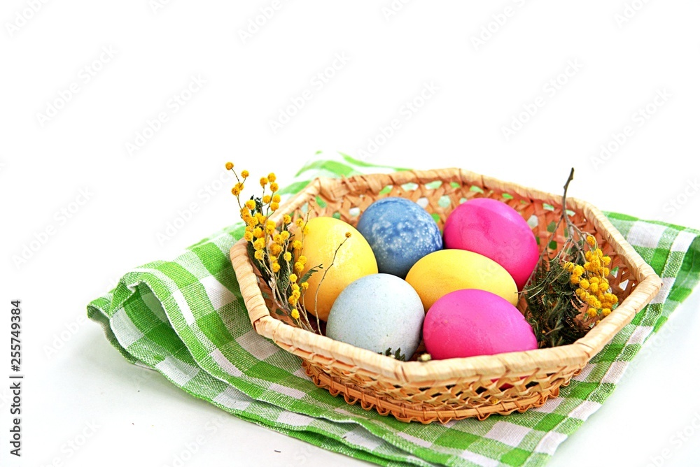 Multi-colored Easter eggs in a wicker basket on a white background. Selective focus.