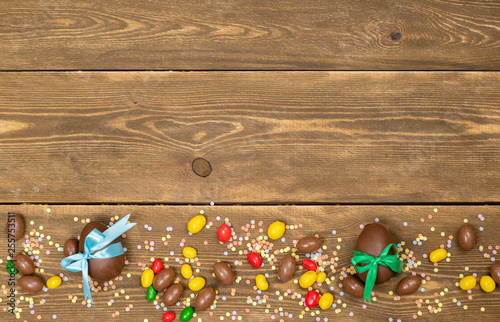 Chocolate Easter eggs and sweets over brown wooden background. backdrop with empty space foe text