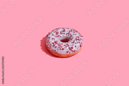 Food design. Close up high quality image of pink glazed donut on coral pink background photo