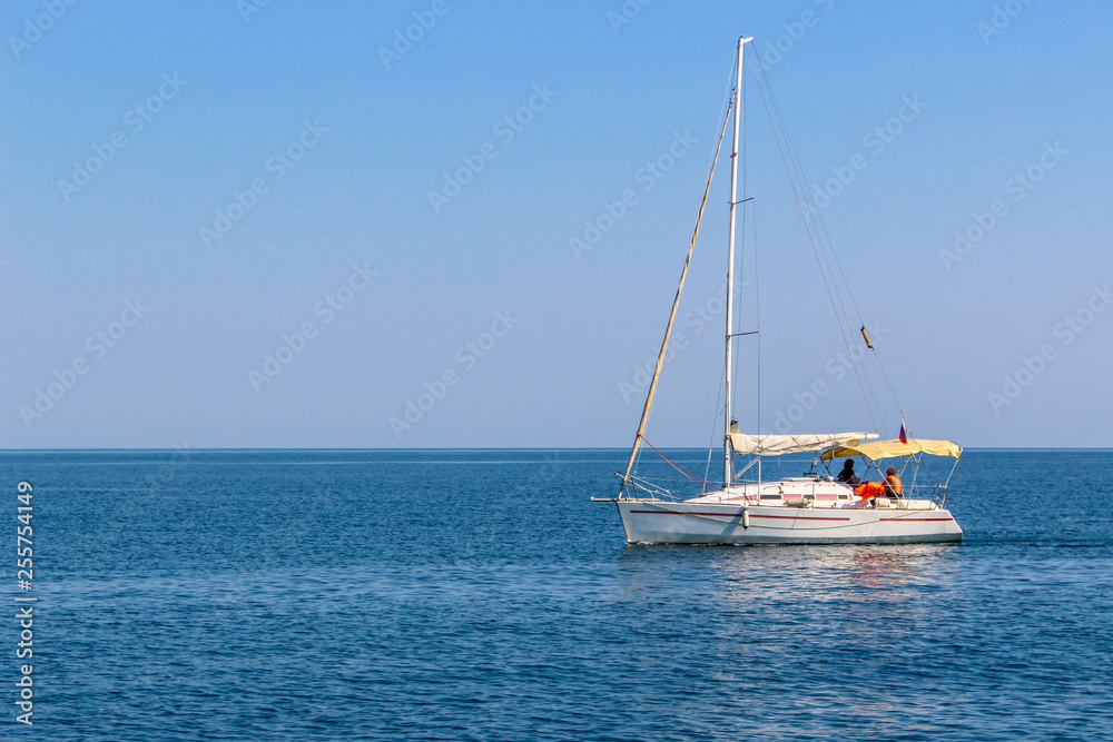 White sailing yacht with lowered sails in the sea White sailing yacht with lowered sails in the sea