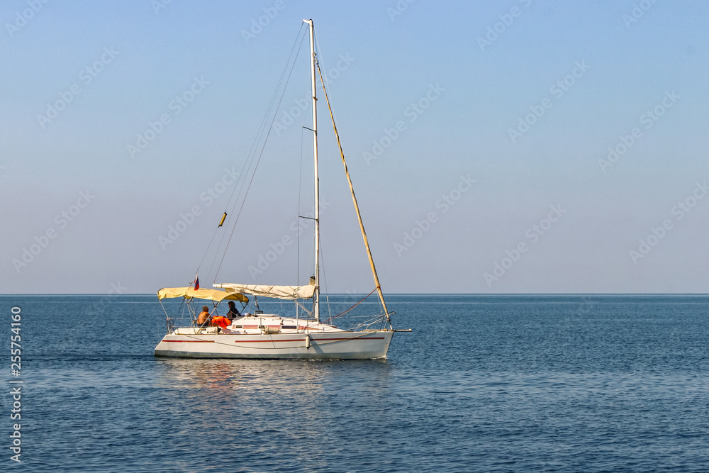 White sailing yacht with lowered sails in the sea