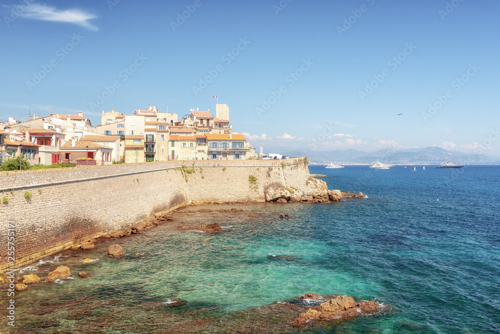 The old city wall along the coast of the French town of Antibes with the old center in the distance