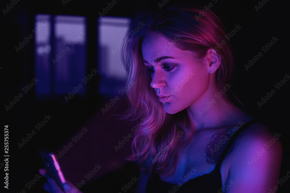 Fototapeta premium Girl using cellphone at night with neon light - pink and blue