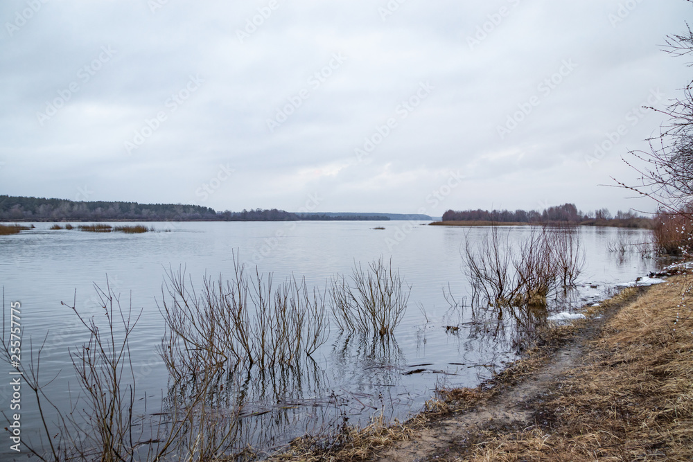 Deep calm river in the spring evening against a cloudy sky