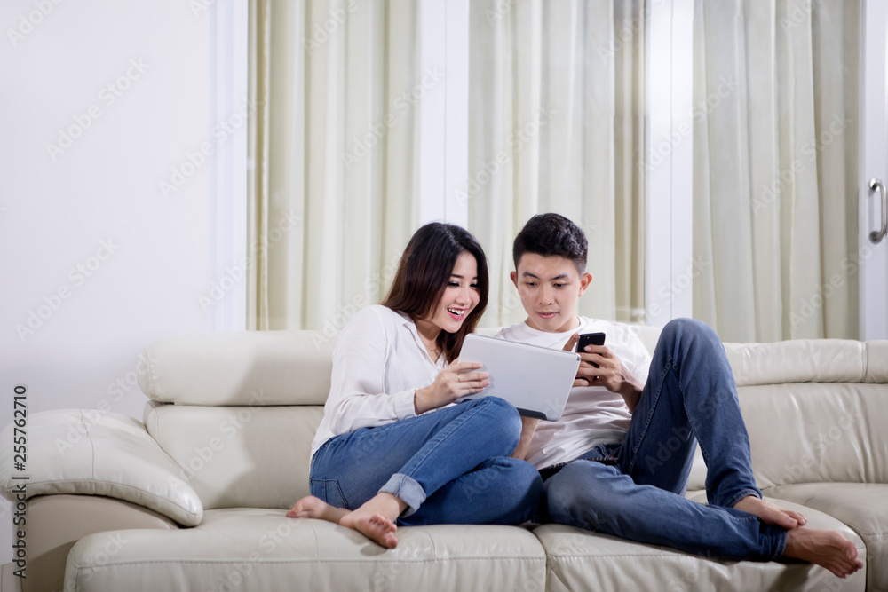 Asian couple with tablet and phone at home