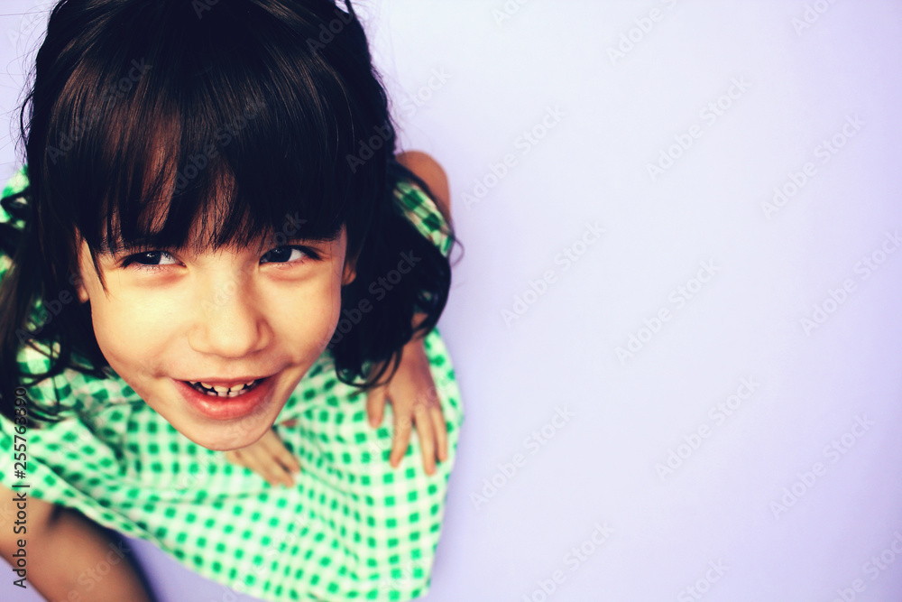 Charismatic child in a white dress with a green square pattern on a light background. Place for inscription Charismatic child in a white dress with a green square pattern on a light background. Place for inscription