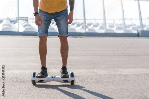 Man in jeans shorts standing on gyro scooter outdoors