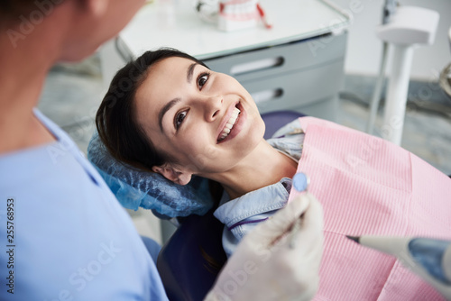 Attractive young lady looking at dentist and smiling