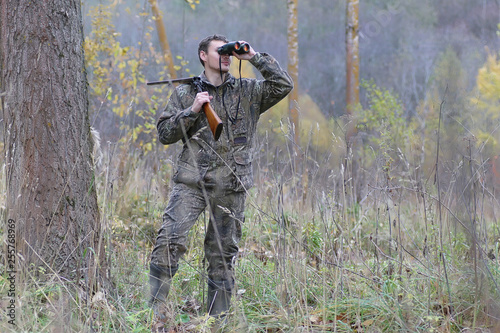 Man in camouflage and with guns in a forest belt on a spring hunt