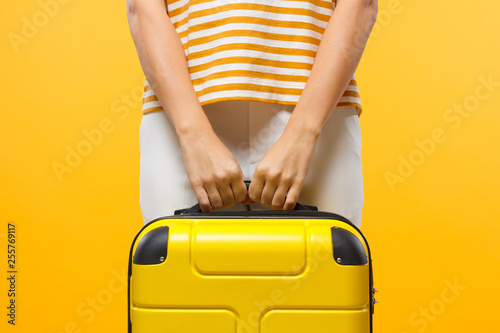 Close-up shot of woman holding yellow suitcase with both hands photo