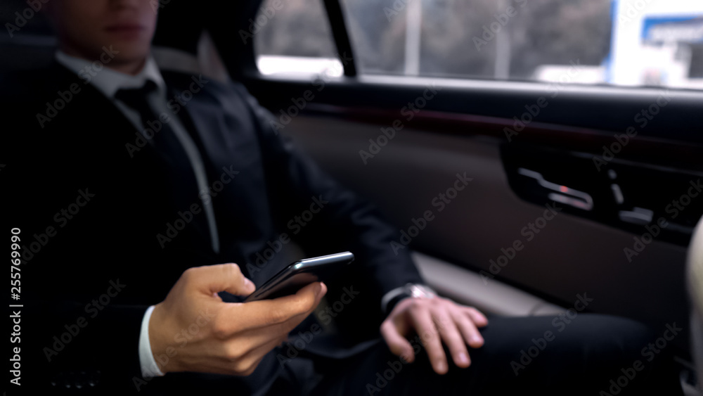 Successful businessman in luxury auto, scrolling smartphone, reading e-mail app