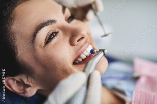 Charming young lady receiving teeth cleaning and polishing at clinic