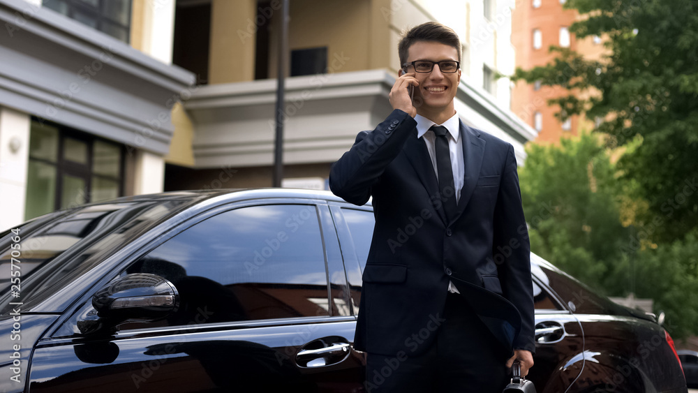Businessman receiving good news, talking on phone near luxury car, success Businessman receiving good news, talking on phone near luxury car, success
