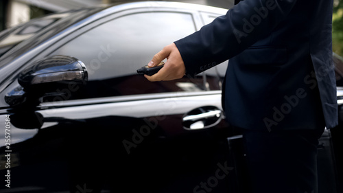 Male in suit pressing remote control of car, alarm system, auto protection
