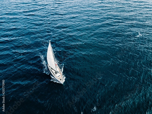 Aerial view of Sailing ship yachts with white sails  in deep blue sea © nblxer