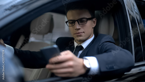 Serious businessman testing new business app on telephone while waiting in car © motortion