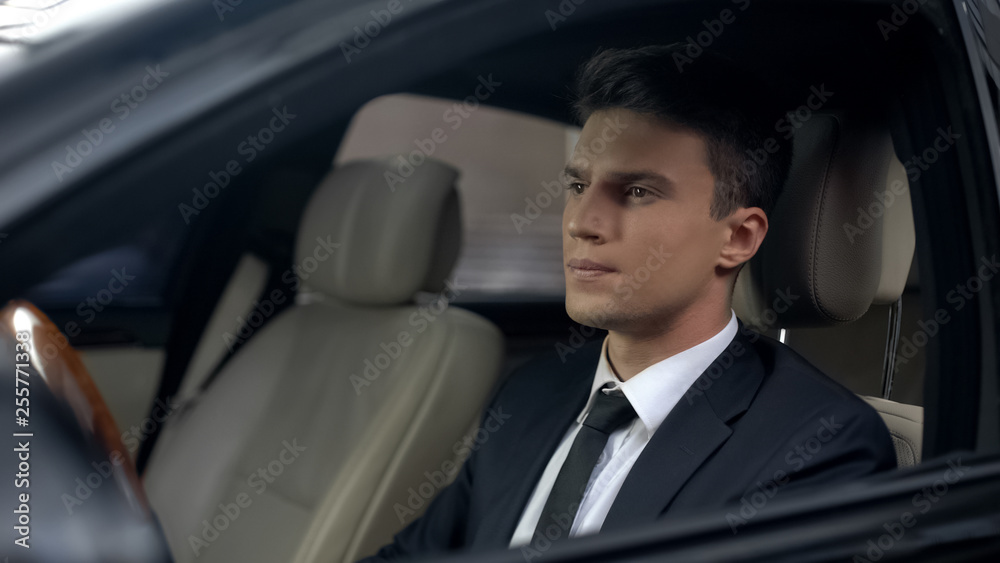 Sad businessman sitting at car in underground parking, preparing for work Sad businessman sitting at car in underground parking, preparing for work