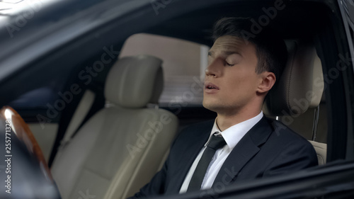Sleepy business person sitting in car, sleeping disorder, stressful lifestyle © motortion