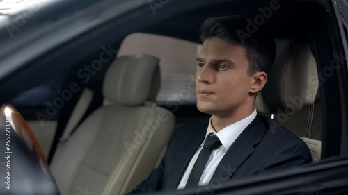 Sad businessman sitting at car in underground parking, preparing for work © motortion