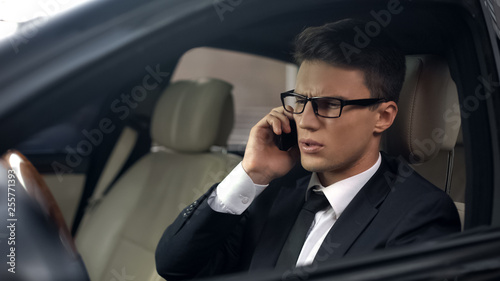 Worried manager talking on smartphone in car, bad news about failed contract © motortion