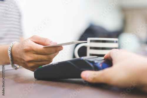 close up customer hand using credit card for paying bill by using payment machine at table in the cafe , contactless payment concept photo