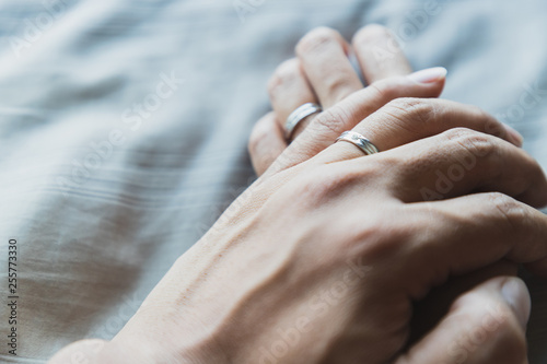 Close up husband and wife hands together on gray beds and beautiful wedding rings