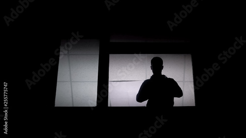 Silhouette of man patient in lunatic at asylum window, psychosocial disabilities