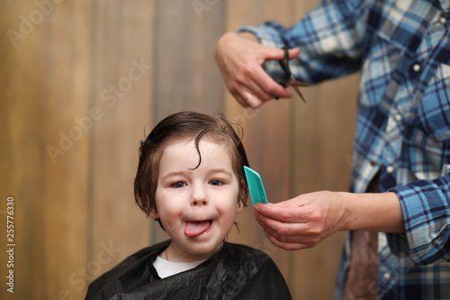 A little boy is trimmed in the hairdresser's bright emotions on face