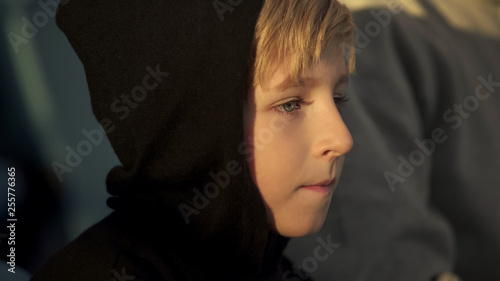 Little boy attentively watching sport game outdoors, supporting favorite team photo