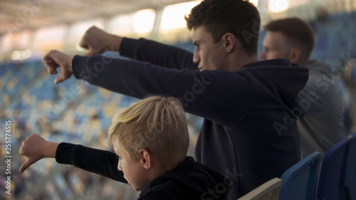 Schilderij op canvas Student fans and little boy booing sport game at stadium, watching junior match