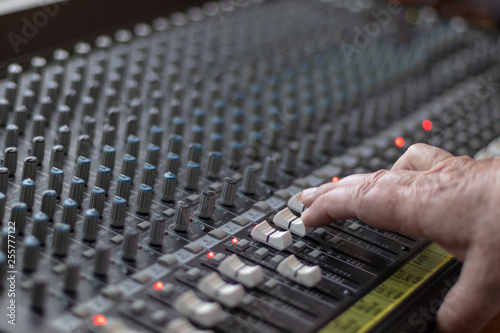 Adult man hand controlling the sliders of a mixer in a studio