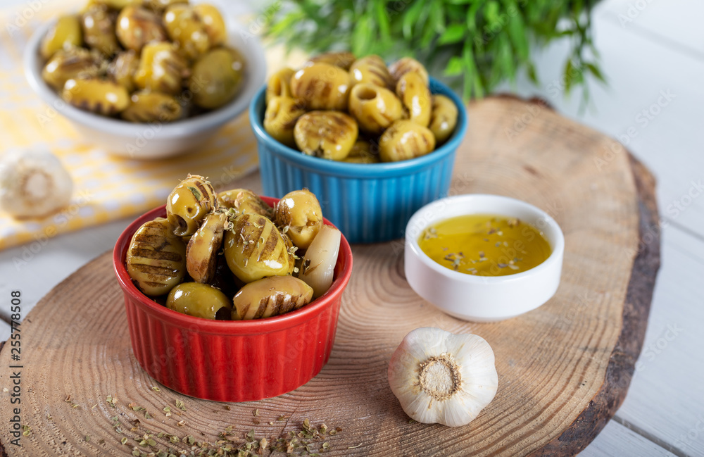 Wooden background with green olives, olive oil, garlic and spices