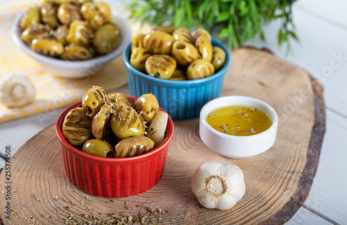 Wooden background with green olives, olive oil, garlic and spices