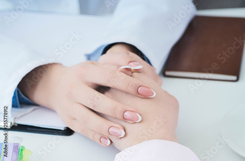 Friendly female doctor hands holding patient hand sitting at the desk for encouragement  empathy  cheering and support while medical examination. Just hands over the table.