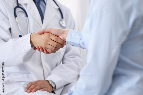 Male doctor and woman patient shaking hands. Partnership in medicine, trust and medical ethics concept