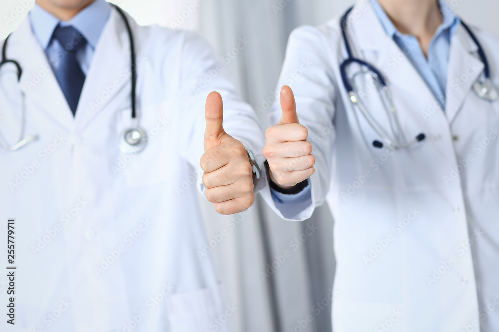 Team of unknown medicine doctors showing OK sign with thumb up close up. Success and high level service in health care, best treatment and customer loyalty and physical concept Team of unknown medicine doctors showing OK sign with thumb up close up. Success and high level service in health care, best treatment and customer loyalty and physical concept