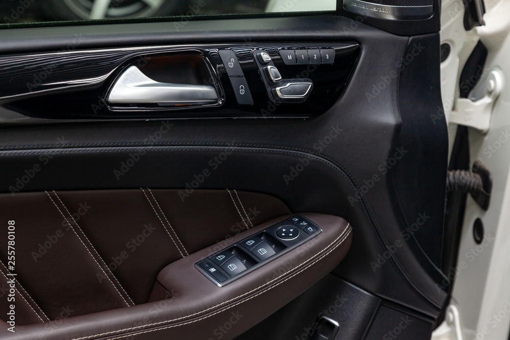 The interior of the luxury business car with a view of the drivers door with buttons, armrest and brown leather after detailing and dry cleaning