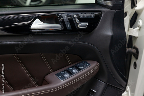 The interior of the luxury business car with a view of the drivers door with buttons, armrest and brown leather after detailing and dry cleaning © Aleksandr Kondratov