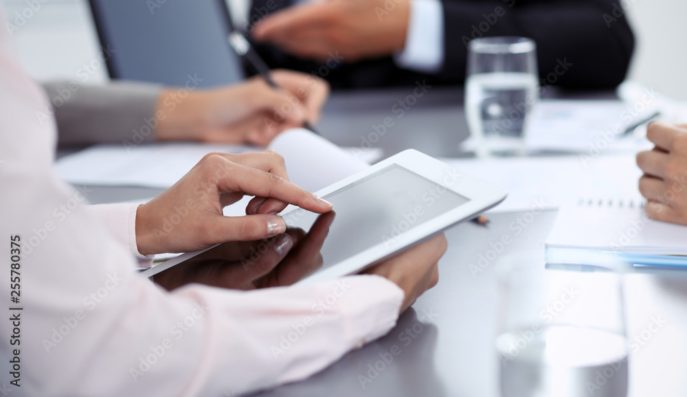 Woman hands using tablet at meeting. Business people group working together in office, close-up. Negotiation and communication concept Woman hands using tablet at meeting. Business people group working together in office, close-up. Negotiation and communication concept