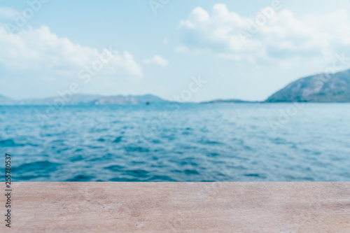Empty wooden table with party on beach blurred background in summer time. The blur cool sea background with wood floor foreground on horizon tropical sandy beach; relaxing outdoors vacation with heave