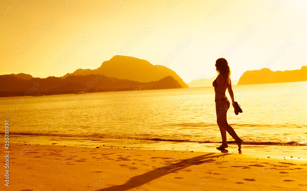 Beautiful girl walking on the beach at sunset