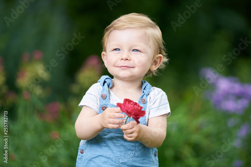 Portrait of a one-year-old girl with blue eyes holding a rose