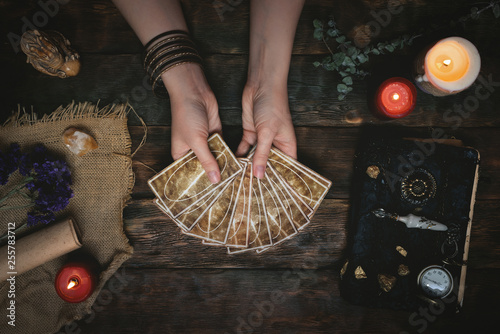 Tarot cards, magic book and fortune teller hands on a wooden table background. Future reading concept. Divination. photo